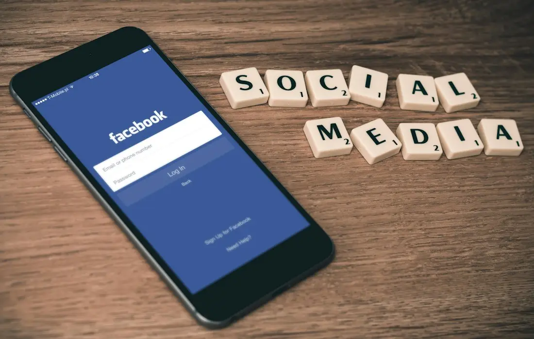 Phone with Facebook open beside social media letter tiles